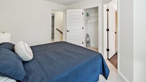 A bedroom with a large bed, a door leading to a closet, and a staircase. - Alto O4 I Modern New Construction 2Bd Apartment (Clarksville)