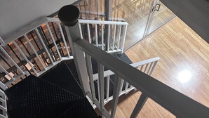 Un escalier avec des rampes blanches menant à un étage inférieur.