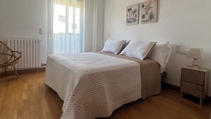 Une chambre à coucher comprenant un lit, une chaise, une table de chevet et un ventilateur de plafond.