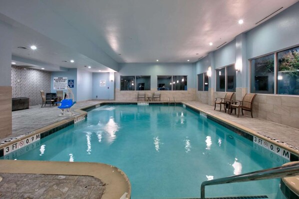 An indoor swimming pool with clear water, a lifeguard chair, and lounge chairs along the sides. - Standard 2 Queen Room w/ Fridge | Pool. Gym. Wi-Fi (Dallas)