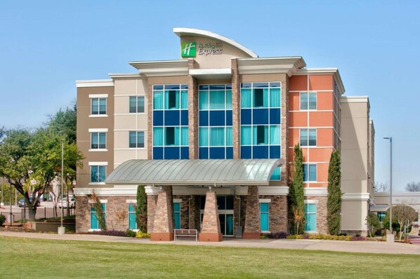 A Holiday Inn Express hotel with a modern design, featuring a prominent green logo, large windows, and a covered entrance.