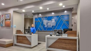 Un área de recepción con dos mostradores, cada uno con un ordenador y un teléfono. Hay obras de arte enmarcadas en la pared y un diseño geométrico azul en la pared detrás de los mostradores.