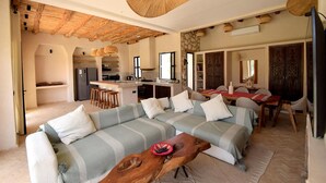Amplia sala de estar con un conjunto de sofás, una mesa de centro de madera y una mesa de comedor con sillas.