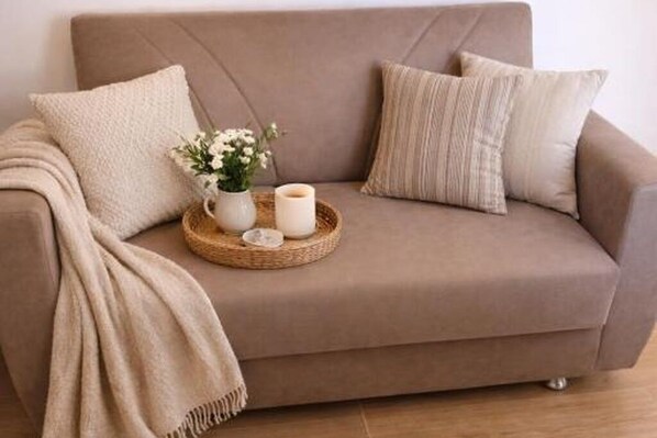 A beige sofa with a woven tray, a vase with flowers, and candles.