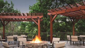 An outdoor patio with stone fire pit seating and a pergola structure. - Close to Dollywood | Free Parking + Breakfast (Pigeon Forge)