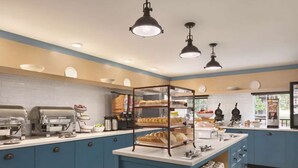 A kitchen area with blue cabinets, a central island with a bread display, and a coffee station. - Close to Dollywood | Free Parking + Breakfast (Pigeon Forge)