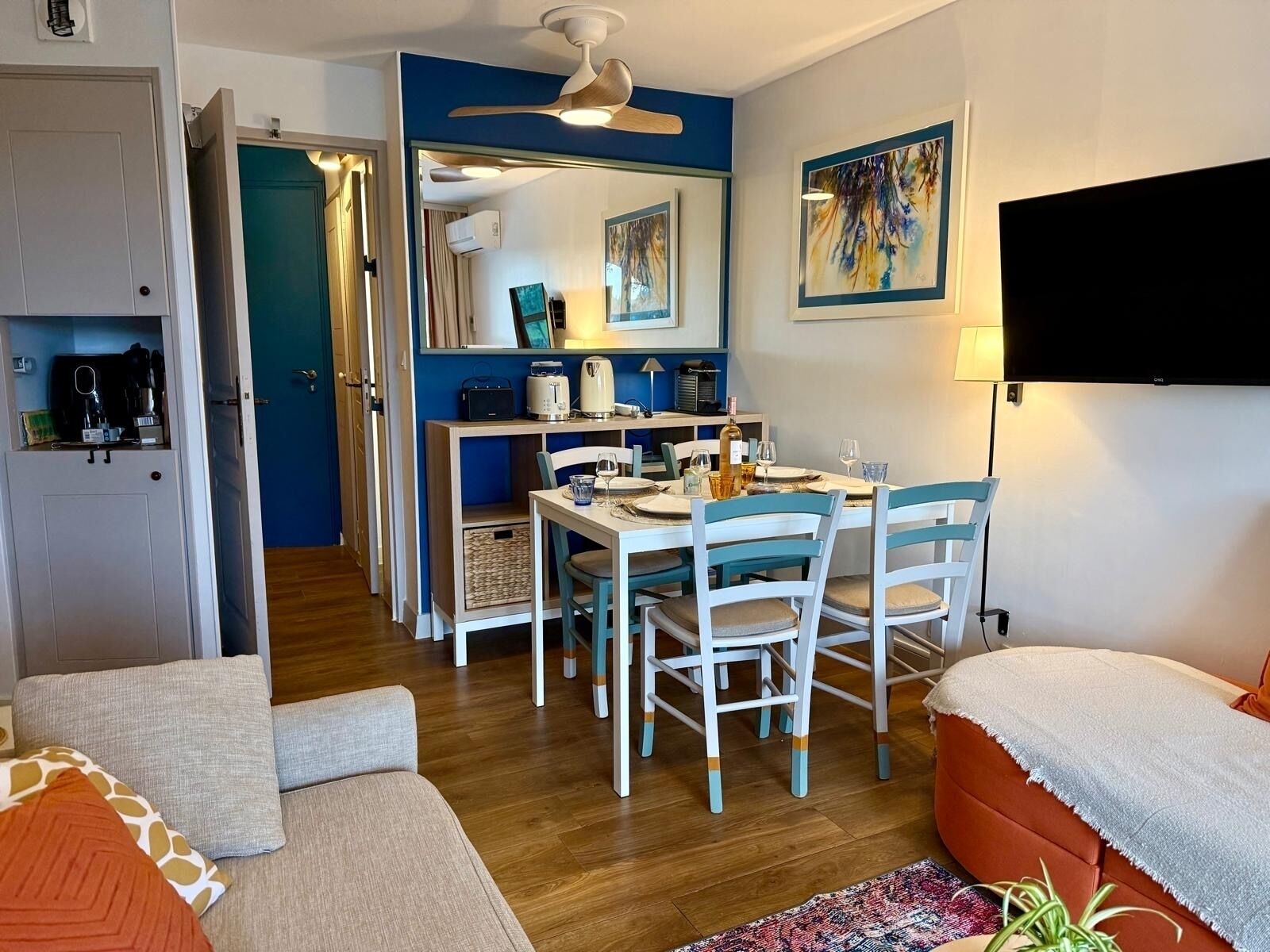 Una sala moderna con comedor, televisor montado en la pared y ventilador de techo.