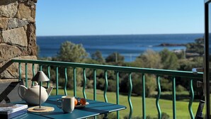 A balcony with a view of the sea, a table with a teapot, a mug, and oranges. - Cazarafa in Cap Esterel 1 Bed, Air-con, Sea & Golf course views, parking, pools. (Saint-Raphaël)