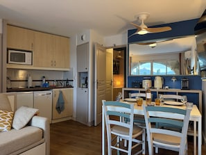 Una cocina moderna con armarios de madera, un microondas y un comedor con una mesa dispuesta para dos.