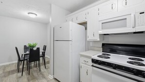 A modern kitchen with white appliances, a dining table with chairs, and a small plant on the table. - Stylish Highland Park 2BR 2BA Stay (Clarksville)