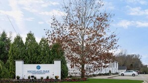 A sign for Highland Park Luxury Apartments with a landscaped lawn and trees. - Stylish Highland Park 2BR 2BA Stay (Clarksville)