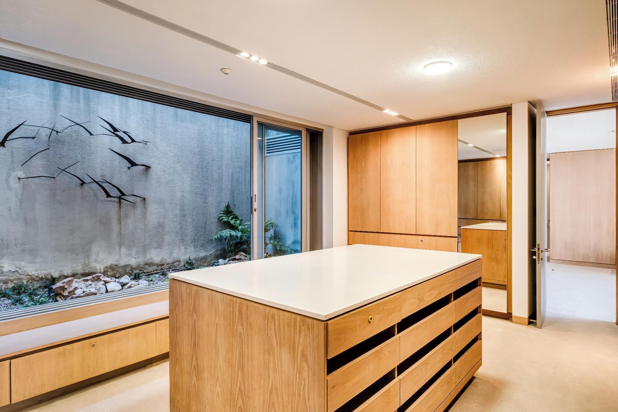 Un baño moderno con muebles de madera, un espejo grande y un ventanal con vistas a un paisaje rocoso.