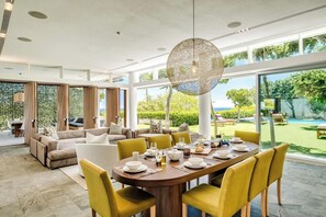 A spacious dining area with a large round table set for six, surrounded by yellow chairs. - Opulent Spacious Fresnaye Sea View Leonotis Villa (Cape Town)