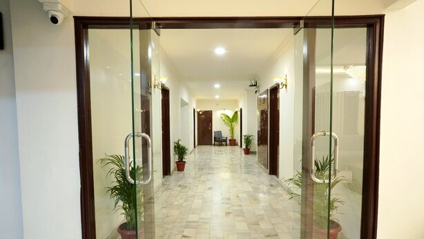A hallway with glass doors, potted plants, and a tiled floor.