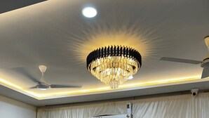 A conference room with a chandelier, ceiling fans, an air conditioning unit, and a table with chairs.