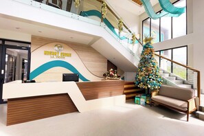Un área de recepción de hotel con diseño moderno, una escalera y un árbol de Navidad.
