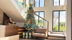 A modern interior with a staircase, a decorative Christmas tree, and a seating area.