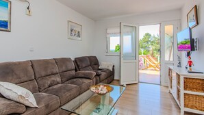 A living room with a brown sofa, a glass coffee table, a white cabinet, and a television. - Holiday Home Florendale with pool (Maslenica)