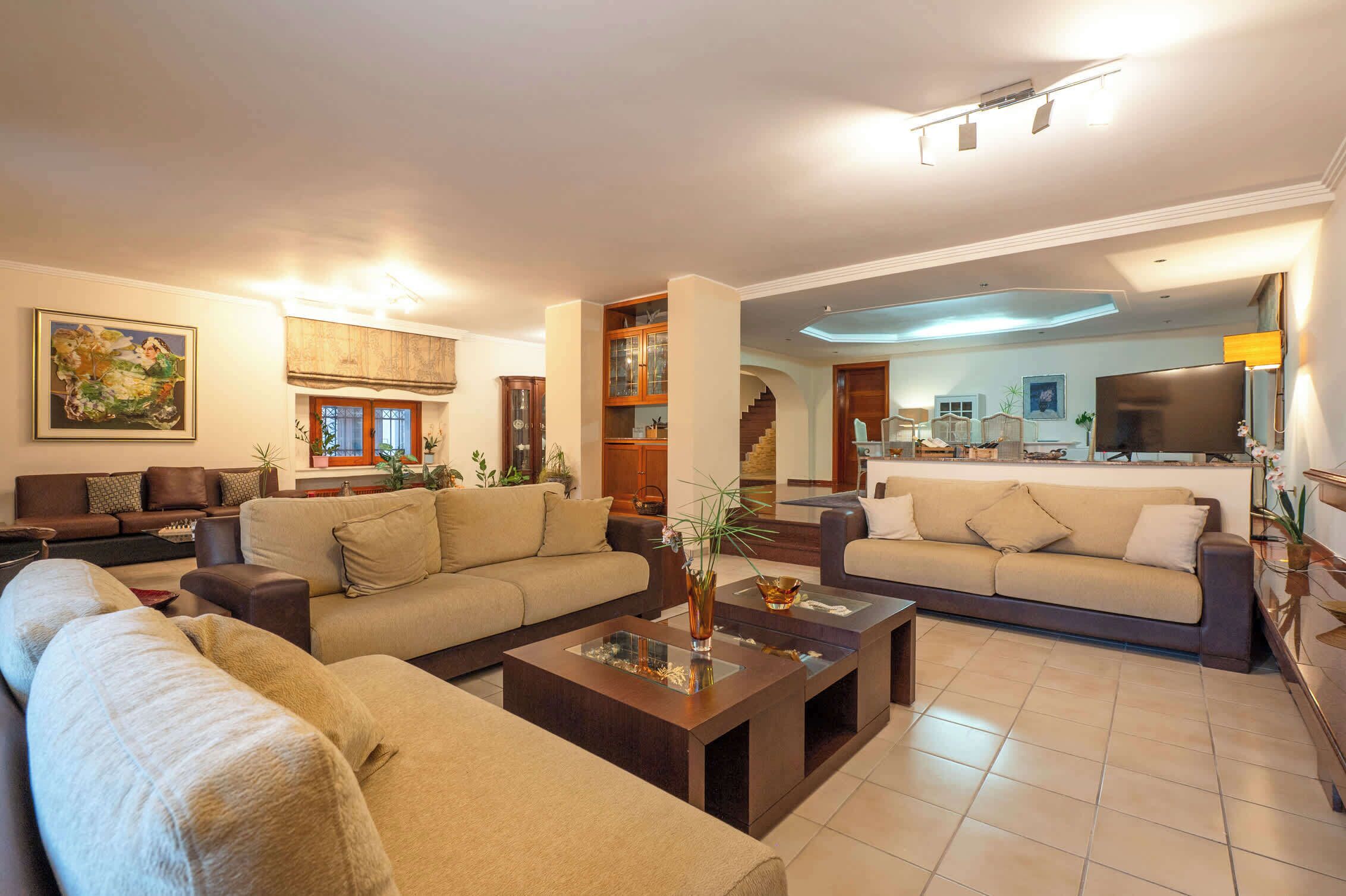 A spacious living room with two sofas, a coffee table, and a dining area with a kitchen in the background.