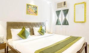 A hotel room with a bed, a bedside telephone, a window with curtains, and a wall-mounted air conditioning unit. - Mayfair Hotel Panjim (Panaji)