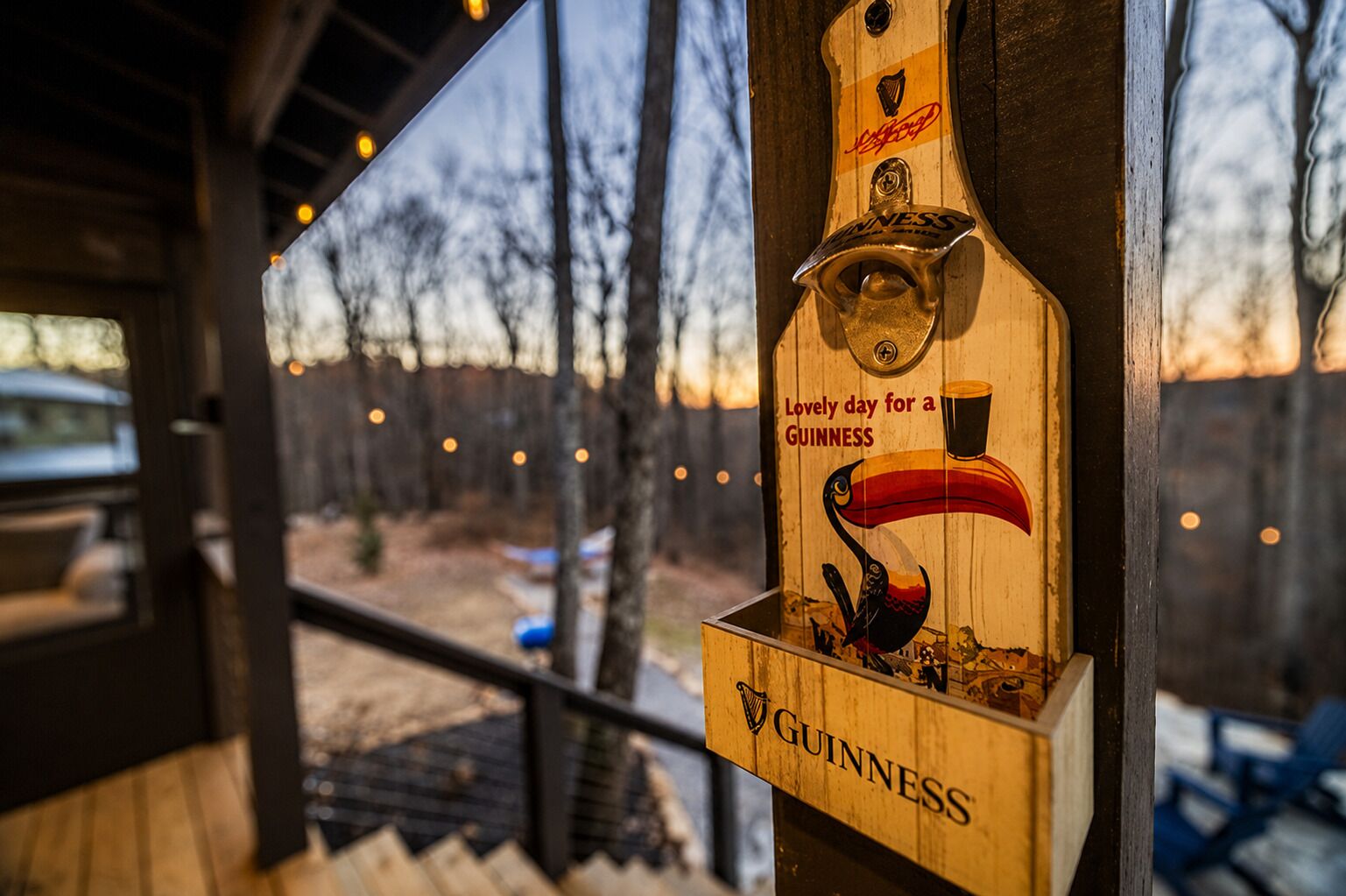 A wooden beer tap with a Guinness logo and a swan illustration, attached to a wooden post.