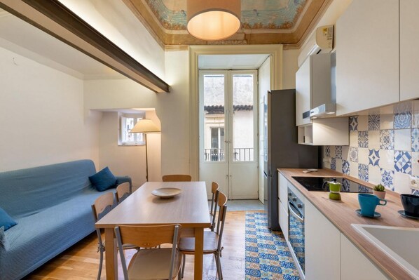 Una cocina compacta con una mesa de comedor, sillas, un sofá y un salpicadero de azulejos.