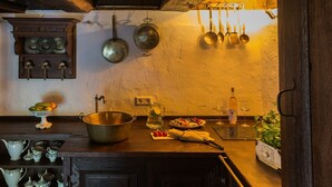Una cocina con un armario de madera, un bol metálico, una jarra y un plato de fruta.