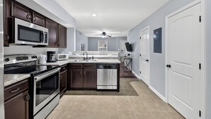 Una cocina moderna con armarios de madera oscura, electrodomésticos de acero inoxidable y encimera blanca.