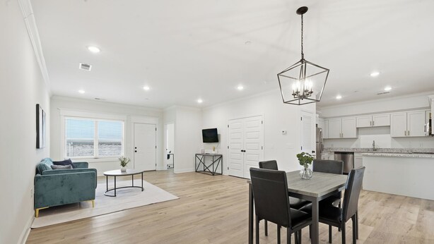 A spacious living area with a dining table and chairs, a sofa, and a kitchen in the background. - Relaxing 2BR Home w/ Contemporary Style (Madison)