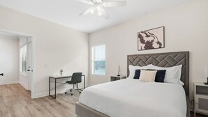 A bedroom with a large bed, a desk, and a chair. - Relaxing 2BR Home w/ Contemporary Style (Madison)