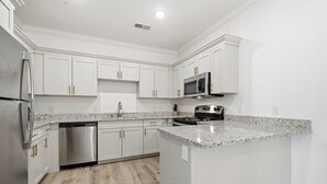 A modern kitchen with white cabinetry, stainless steel appliances, and a granite countertop. - Relaxing 2BR Home w/ Contemporary Style (Madison)
