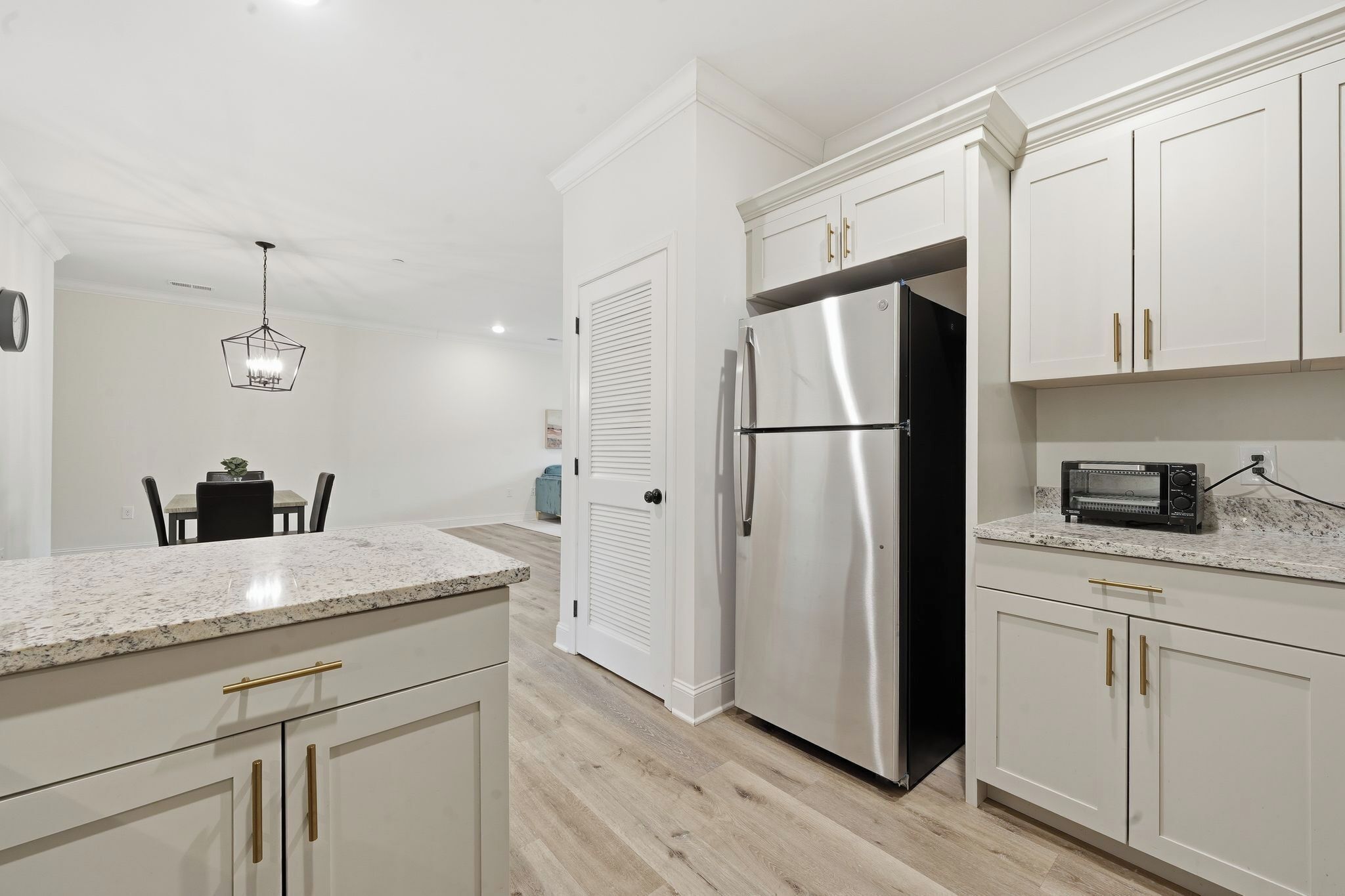 A modern kitchen with white cabinetry, a stainless steel refrigerator, and a countertop with a toaster.