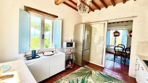 A compact kitchen with a refrigerator, microwave, and a dining area with chairs. - Lovely Apartment with Breathtaking Views in Cool Umbrian Village (Gioiella)
