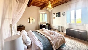 A bedroom with a canopy bed, a mirror, a radiator, and a window with curtains. - Lovely Apartment with Breathtaking Views in Cool Umbrian Village (Gioiella)