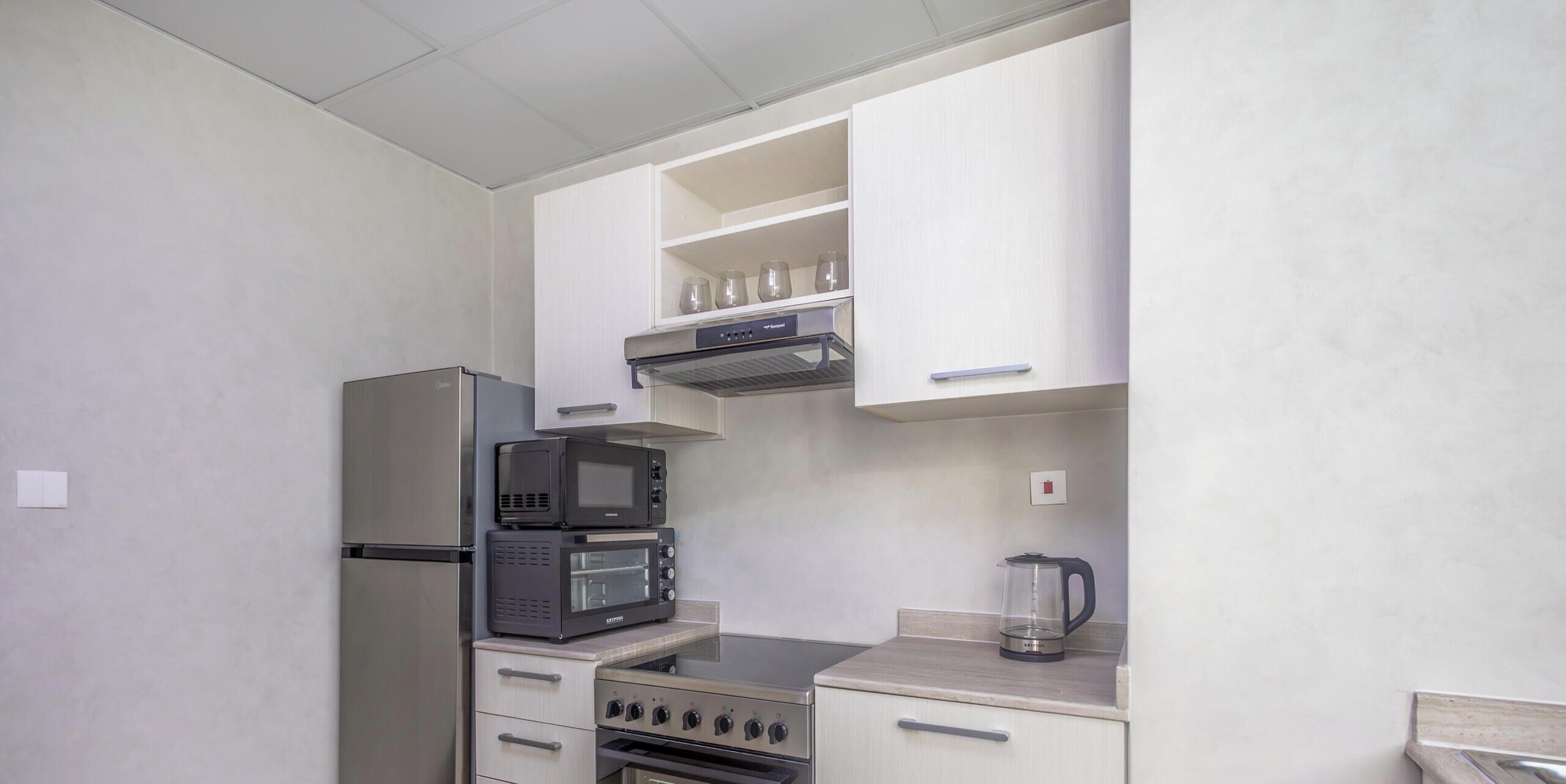 A compact kitchen with a refrigerator, microwave, oven, and a coffee maker.