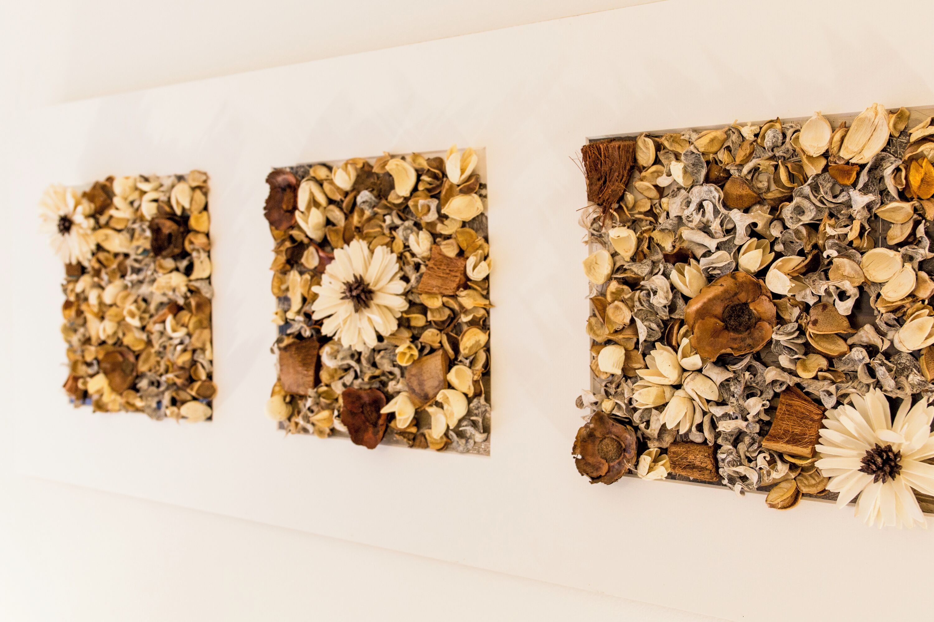 Three square artworks on a white wall.