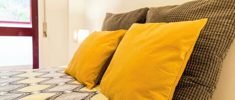 Un lit avec une couvre-lit à motifs et deux oreillers, un jaune et un marron.