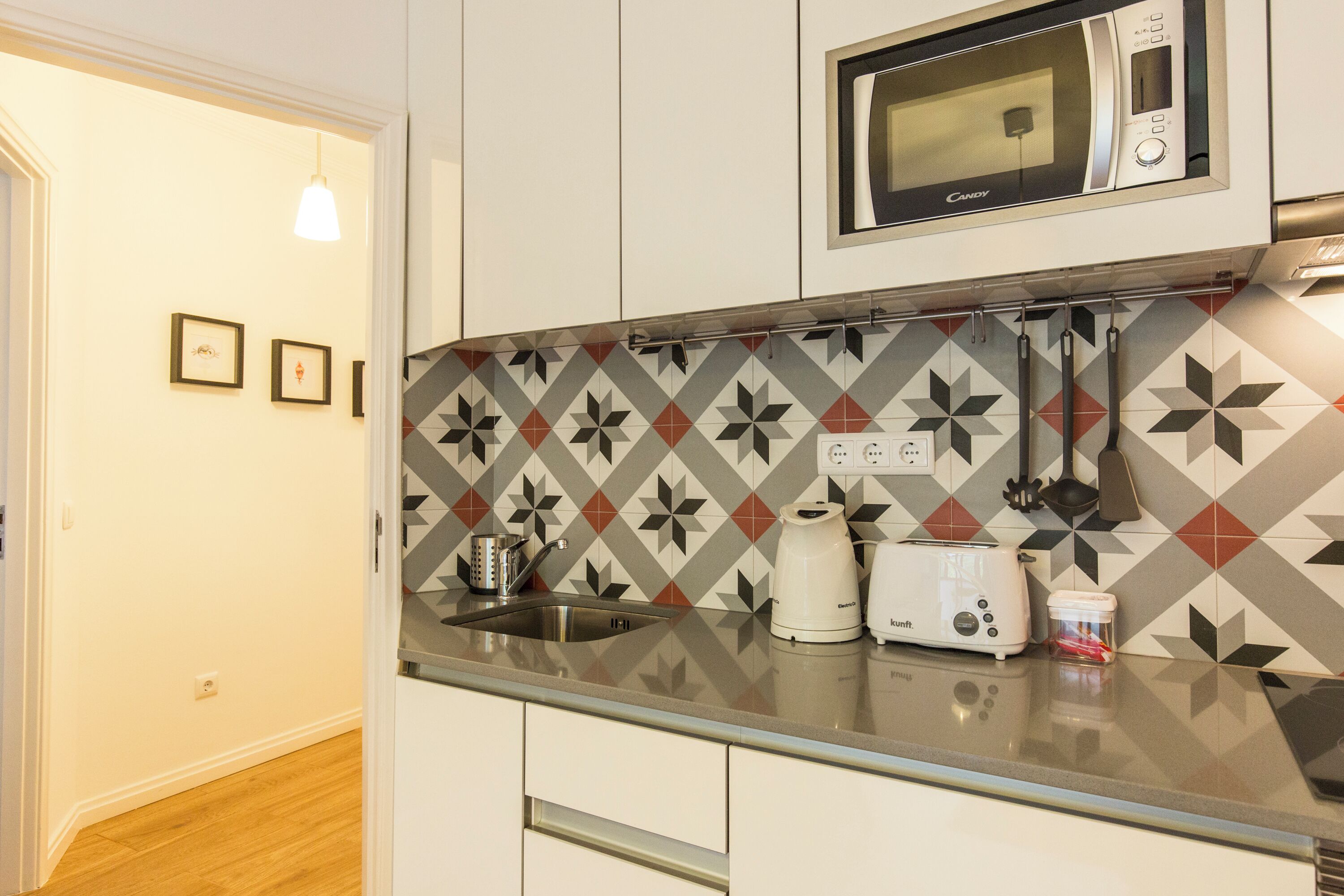 Una cocina equipada con microondas, tostadora, hervidor y un salpicadero con diseño.