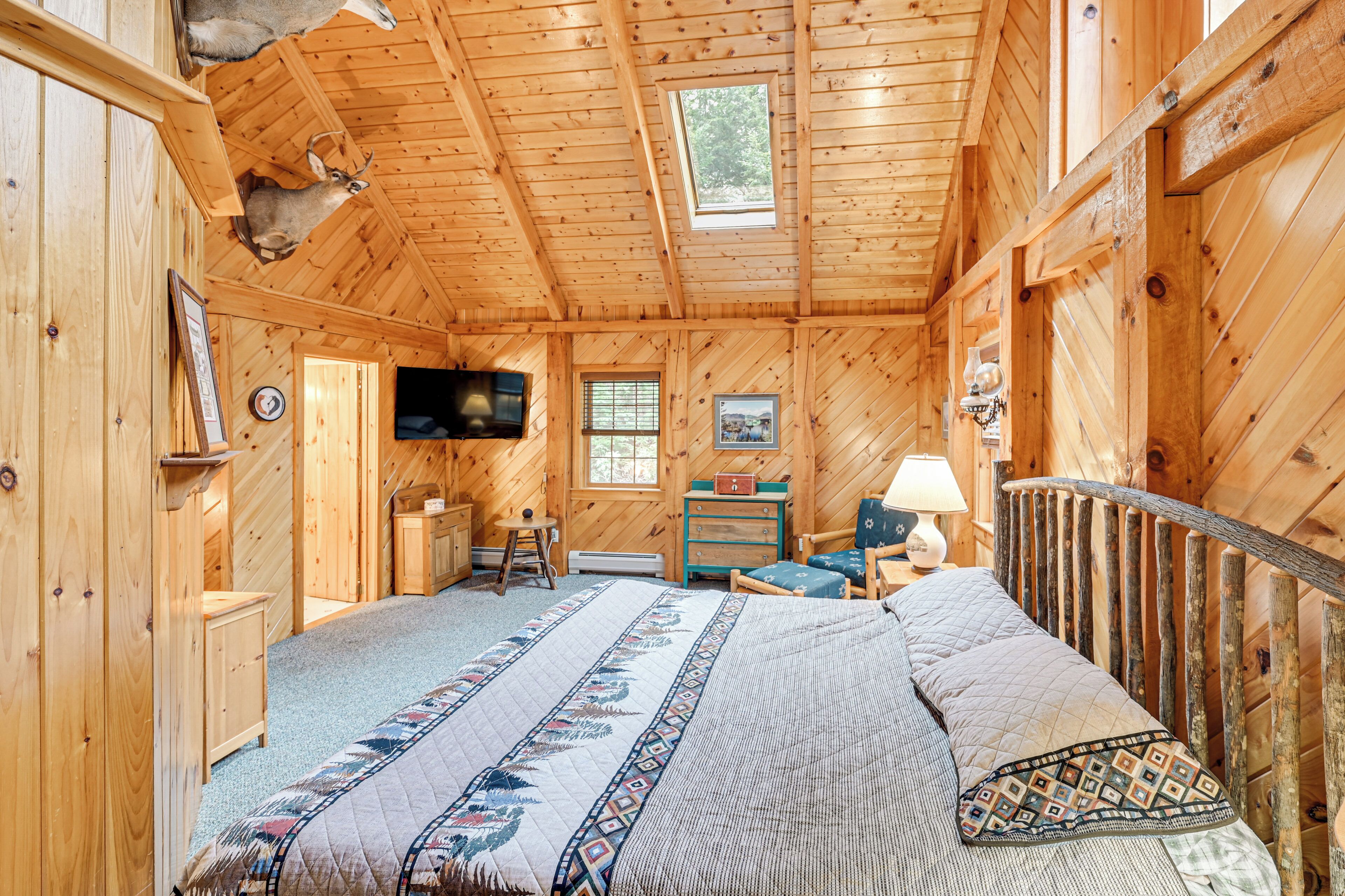 Ein Schlafzimmer in einer Blockhütte mit Bett, Schreibtisch, Stuhl, Fernseher und Fenster.