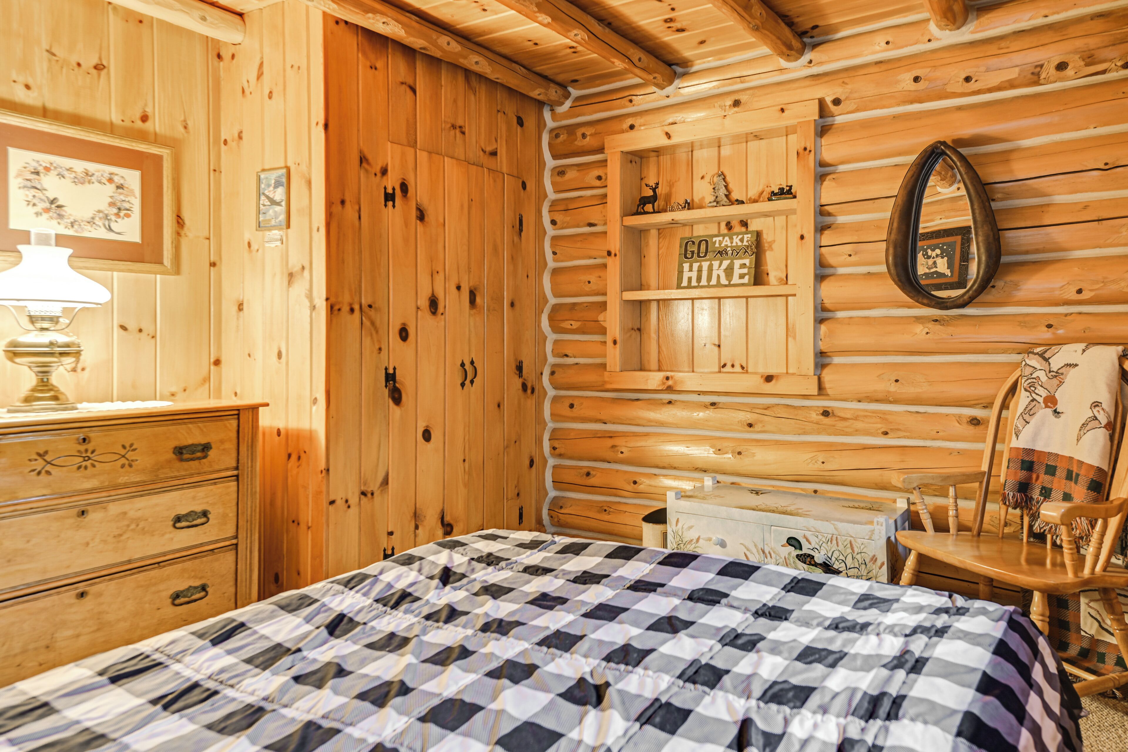 Ein Blockhauszimmer mit Bett, Schminktisch und Ablagefläche mit einem Schild.