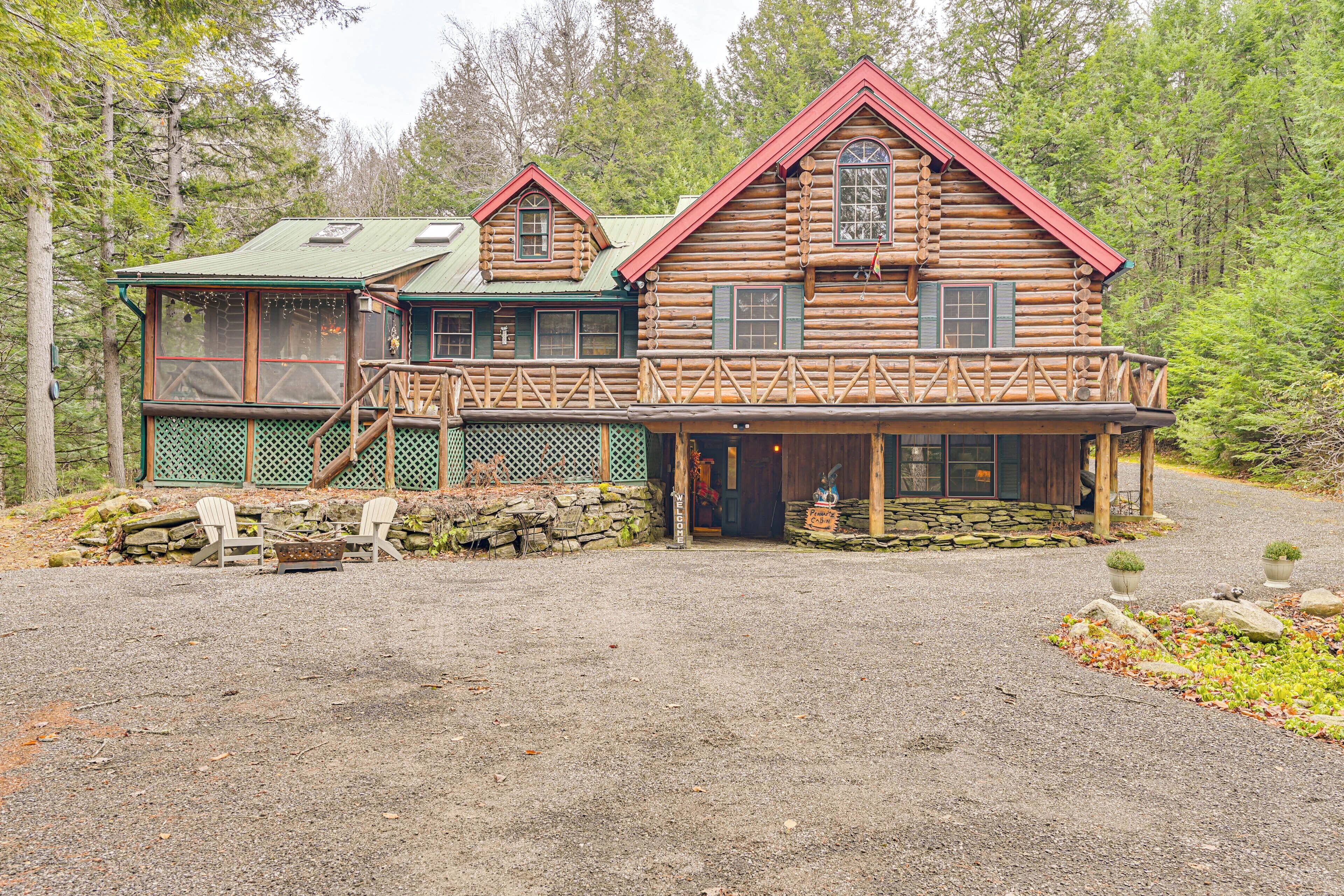 A log cabin with a porch and a separate building with a green roof.