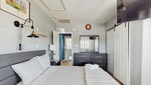 Een slaapkamer met een groot bed, een dressoir, een spiegel en een plafondventilator.