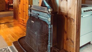A traditional wood-burning stove with a decorative chimney, a vintage-style oven, and a wooden interior. - Bay-view Getaway w/ Deck Between Camden & Belfast! (Lincolnville)