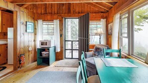 Een gezellig houten interieur met een eethoek, een tafel, stoelen, een magnetron en een brandblusser.