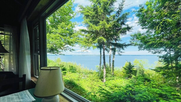 Een kamer met uitzicht op een meer en bos.