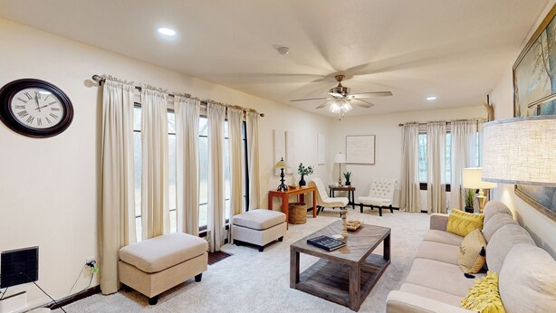 A living room with a ceiling fan, a clock, a sofa, a coffee table, and a television. - 3BR Private Stay w/ Game Room & Fireplace (Indianapolis)