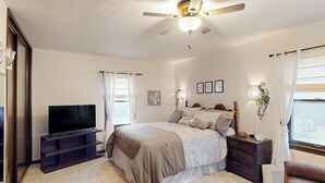 A bedroom with a bed, a TV, a nightstand, a chair, and a window with curtains. - 3BR Private Stay w/ Game Room & Fireplace (Indianapolis)