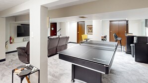 A modern living room with a ping pong table, a sofa, and a television. - 3BR Private Stay w/ Game Room & Fireplace (Indianapolis)