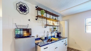 A compact kitchen with a microwave, sink, and shelves with glassware and plants. - Dog-friendly Apt w/ Fenced Yard in Winter Park (Winter Park)