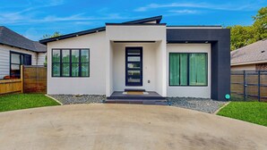A modern two-story house with a concrete driveway, large windows, and a black door. - Modern Dallas Retreat 5 Mi to Dtwn: Pets Welcome (Dallas)